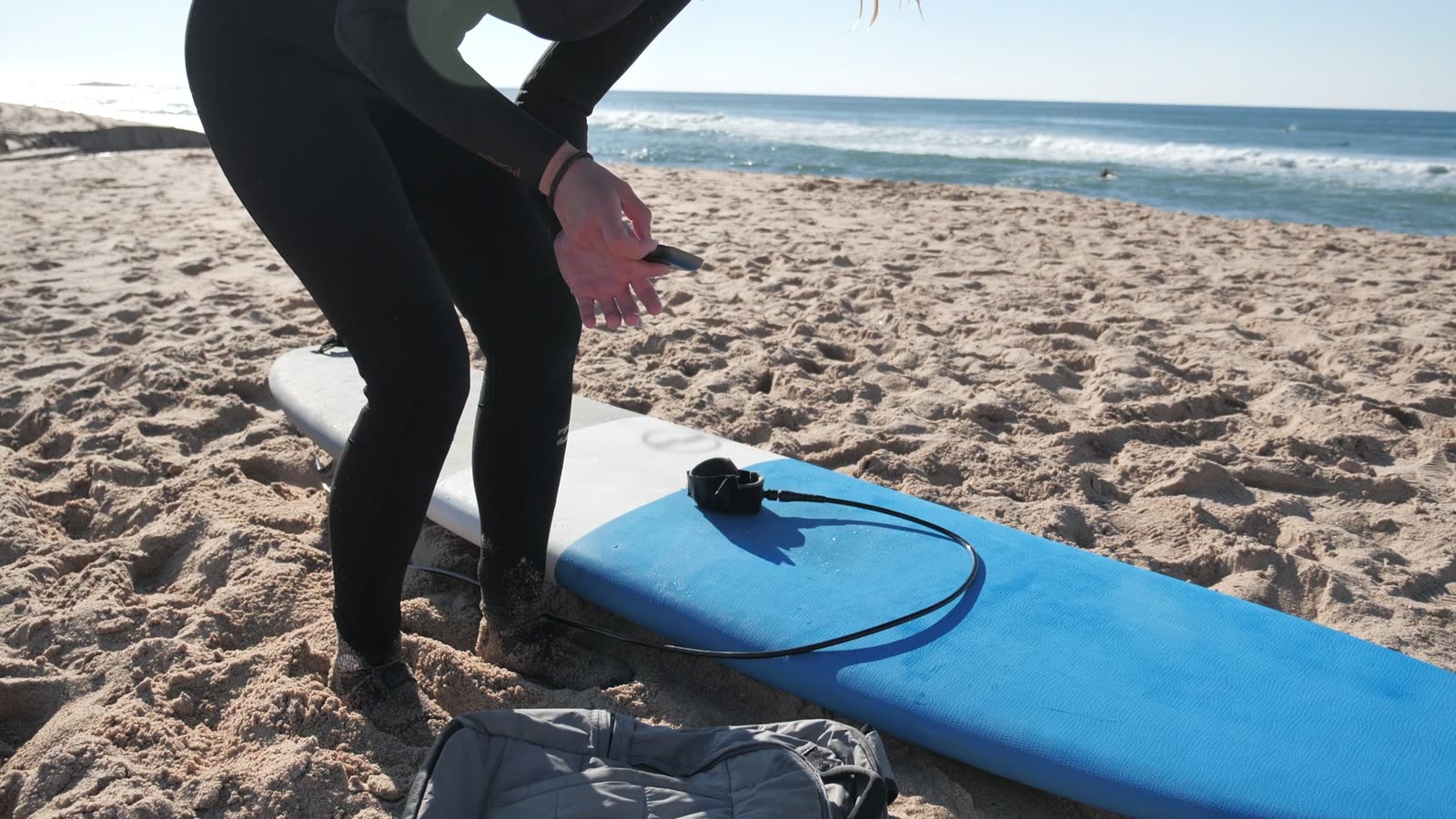 A surfer getting ready beside a surfboard on the beach
